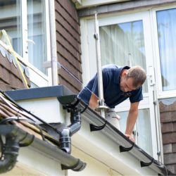 Roofer repairing a gutter on a residential house